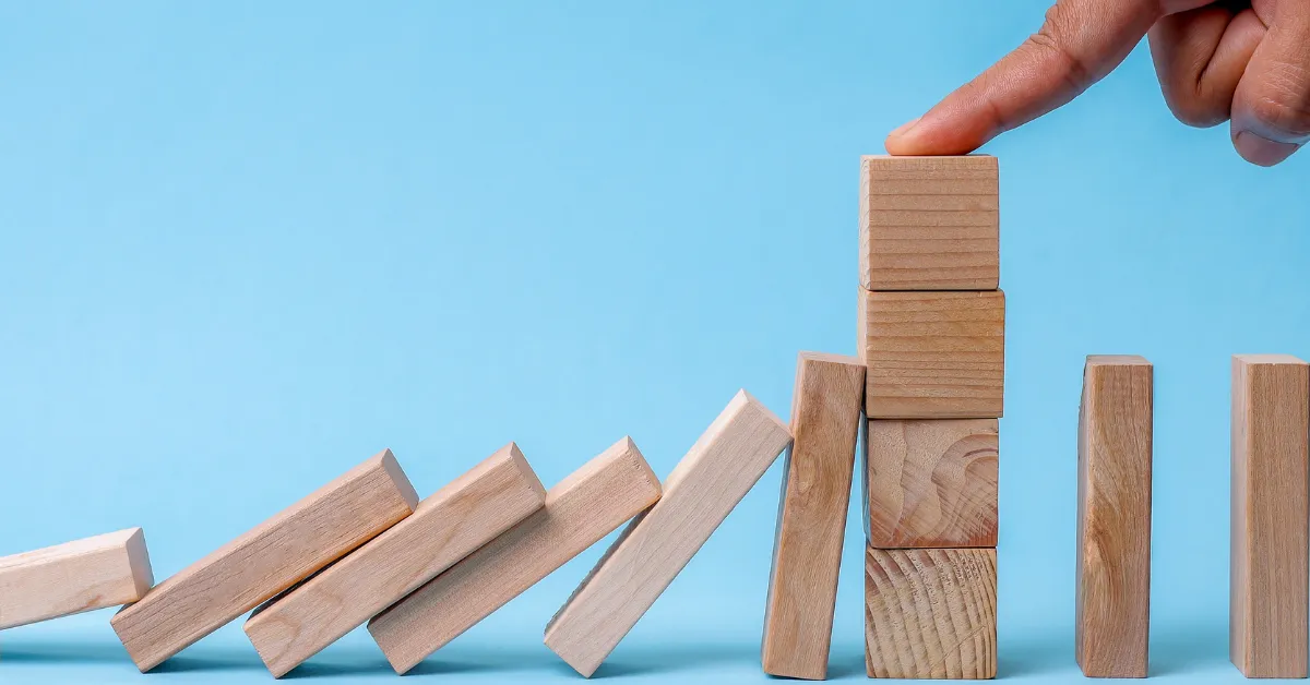 A hand stabilizing wooden dominoes to prevent them from falling
